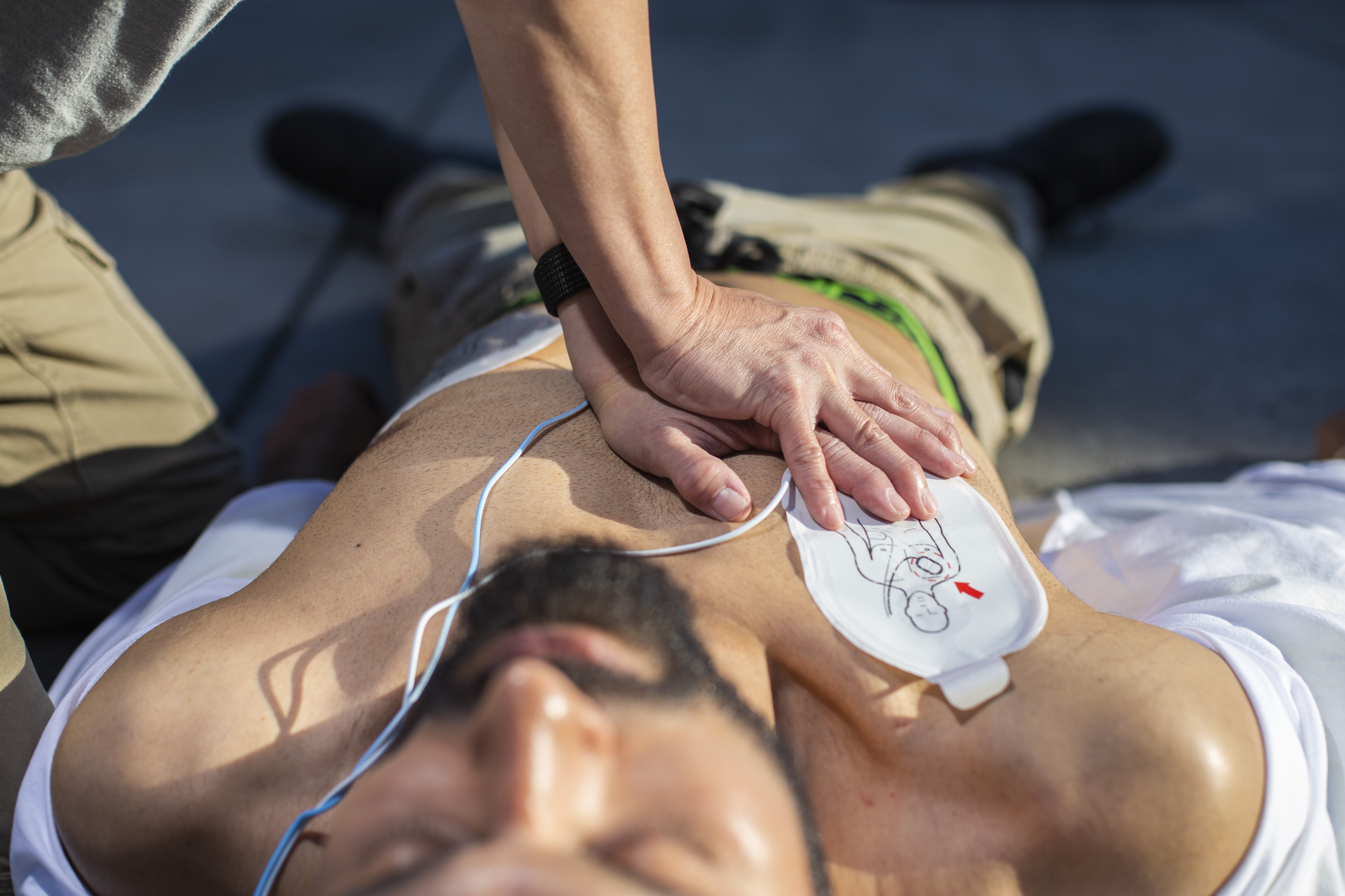 Person performing CPR on a bearded man on the floor