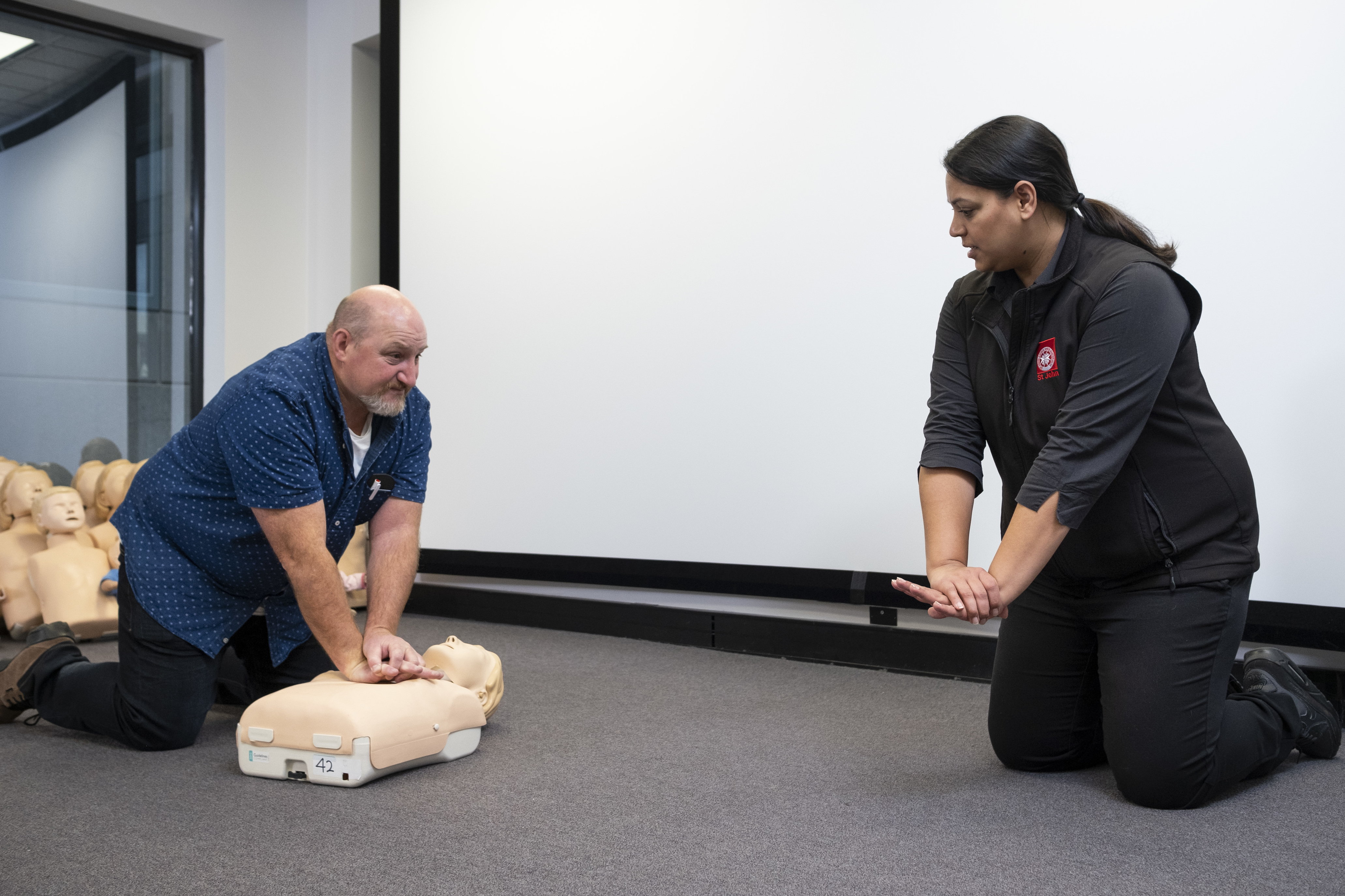 St John first aid training trainer with student on CPR manikin 